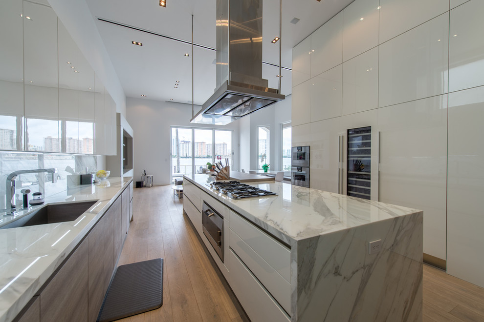 Inspiration for a large modern galley light wood floor and brown floor enclosed kitchen remodel in Miami with an undermount sink, flat-panel cabinets, white cabinets, marble countertops, gray backsplash, stone slab backsplash, paneled appliances, an island and multicolored countertops