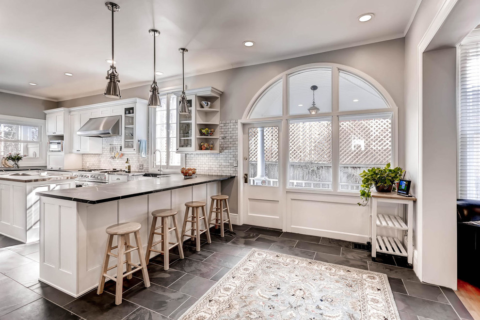 Inspiration for a large timeless l-shaped ceramic tile open concept kitchen remodel in Denver with a farmhouse sink, recessed-panel cabinets, white cabinets, soapstone countertops, gray backsplash, subway tile backsplash, stainless steel appliances and an island