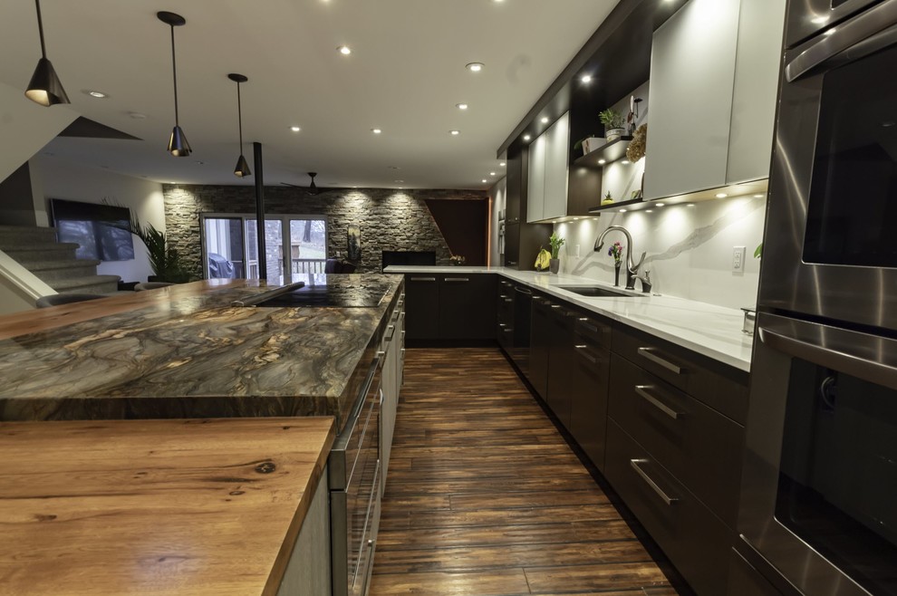 This is an example of a large bohemian l-shaped kitchen/diner in Detroit with flat-panel cabinets, brown cabinets, wood worktops, multi-coloured splashback, marble splashback, stainless steel appliances, medium hardwood flooring, an island, multi-coloured floors and multicoloured worktops.