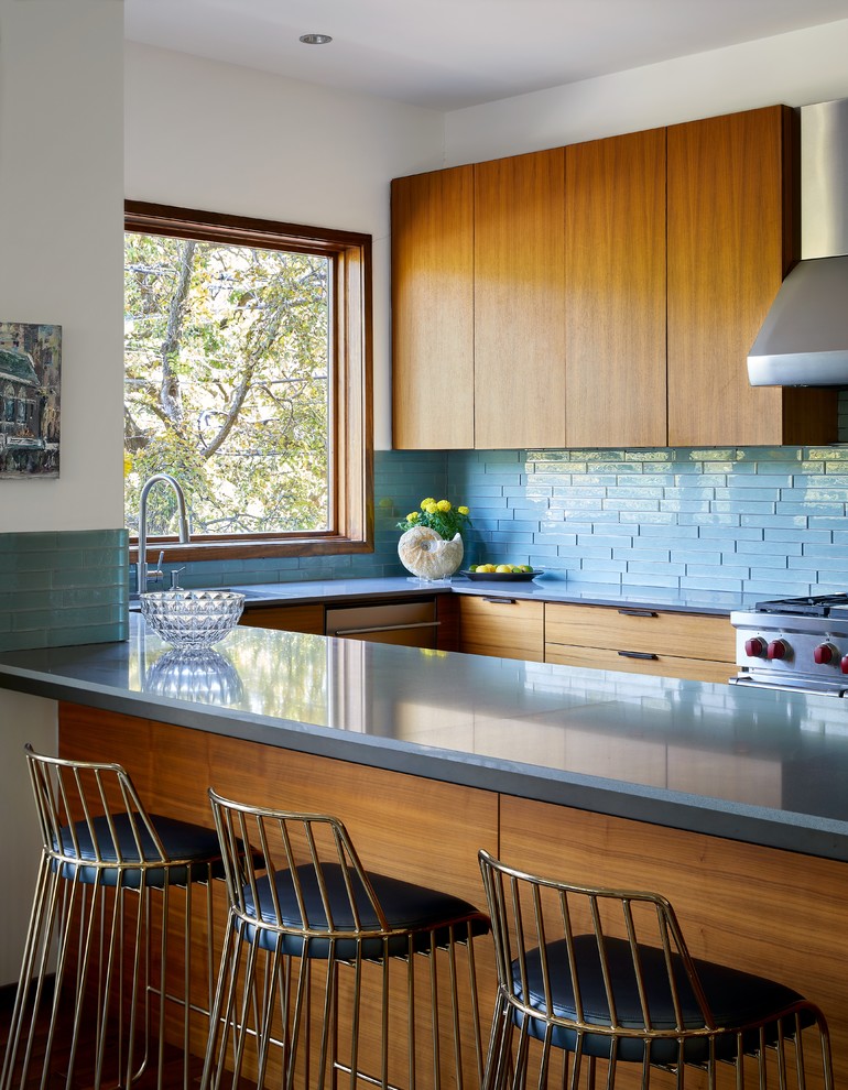 Immagine di una cucina contemporanea con ante lisce, ante in legno scuro, paraspruzzi blu, elettrodomestici in acciaio inossidabile e penisola