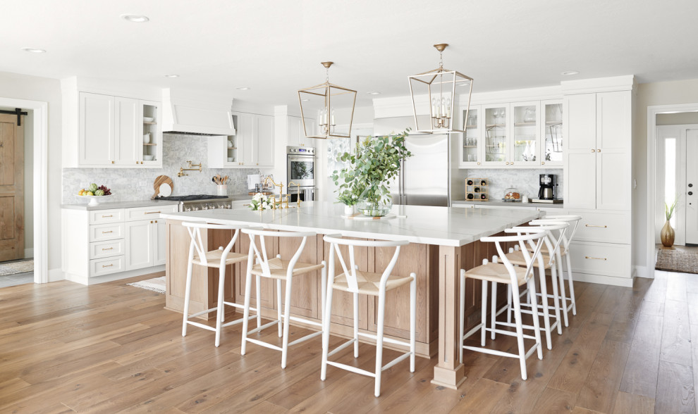 This is an example of a large scandinavian u-shaped kitchen/diner in San Francisco with a belfast sink, recessed-panel cabinets, white cabinets, quartz worktops, white splashback, marble splashback, stainless steel appliances, light hardwood flooring, an island, beige floors and white worktops.