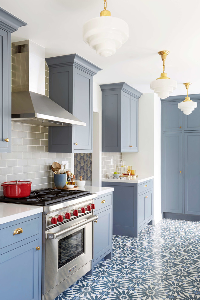 Eklektisk inredning av ett kök, med blå skåp, grått stänkskydd, stänkskydd i keramik och cementgolv