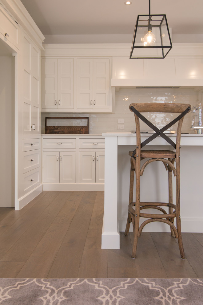 Immagine di una cucina minimalista di medie dimensioni con parquet chiaro, pavimento beige, ante a persiana, ante bianche, paraspruzzi bianco, paraspruzzi con piastrelle in ceramica e elettrodomestici bianchi