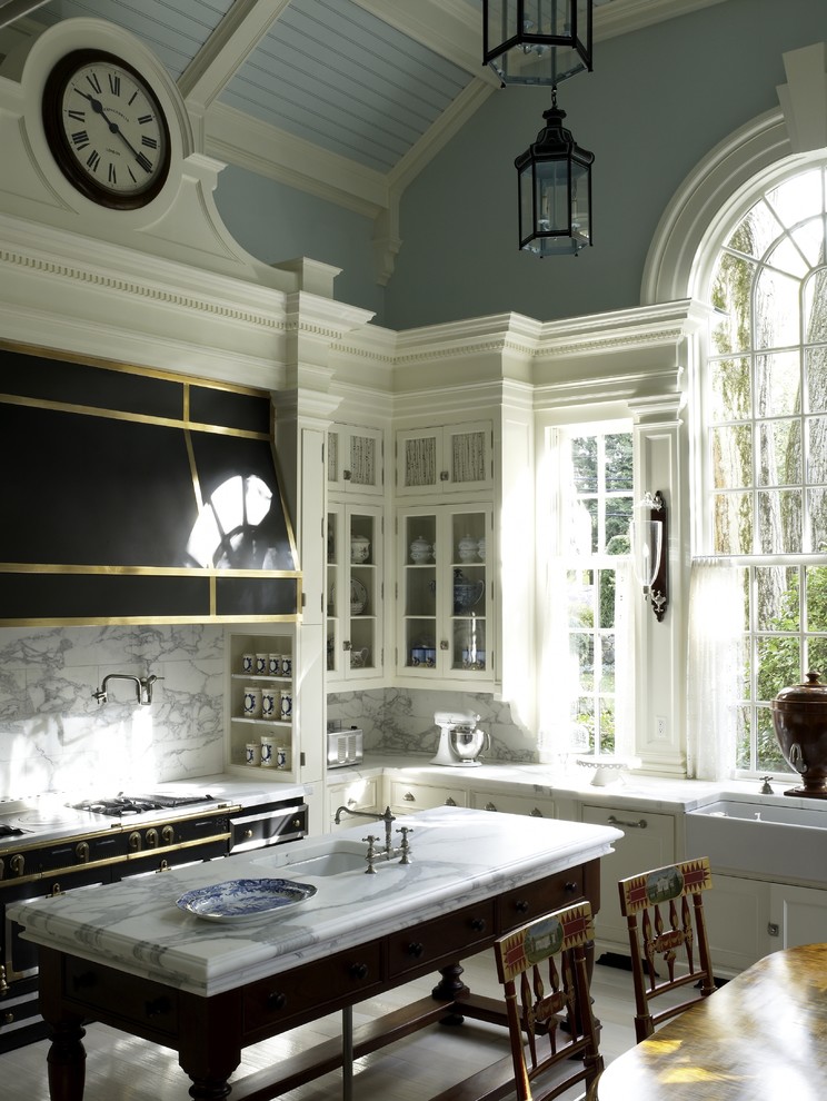 Example of a classic eat-in kitchen design in New York with a farmhouse sink, black appliances, glass-front cabinets, white cabinets, marble countertops, white backsplash and marble backsplash