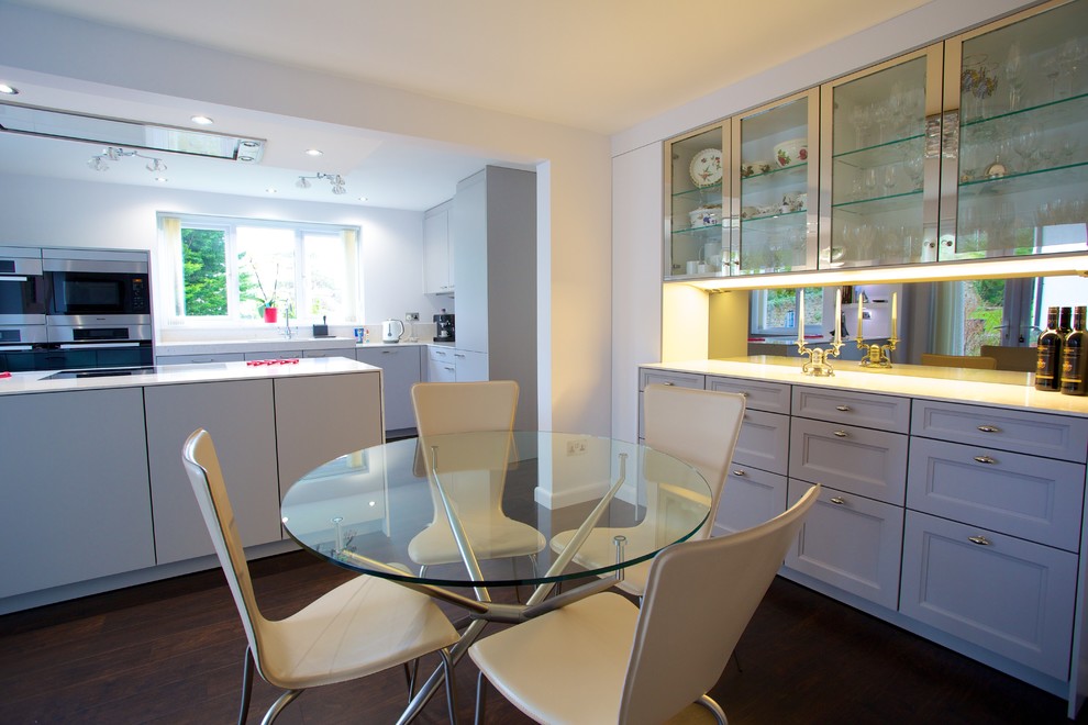 This is an example of a small contemporary galley kitchen/diner in Hampshire with a submerged sink, flat-panel cabinets, grey cabinets, composite countertops, grey splashback, stainless steel appliances and an island.