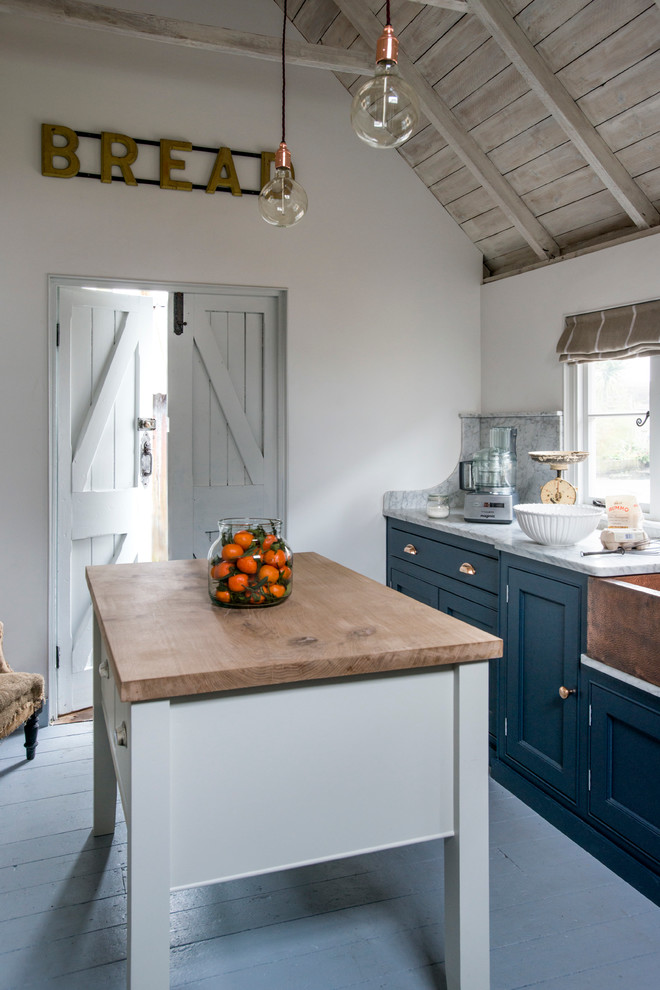 Modelo de cocina de estilo de casa de campo con fregadero sobremueble, armarios con rebordes decorativos, puertas de armario azules, suelo de madera pintada y una isla