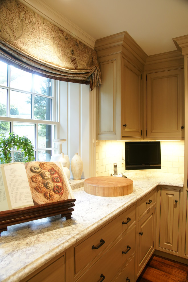 Inredning av ett klassiskt mellanstort, avskilt l-kök, med en enkel diskho, luckor med upphöjd panel, gröna skåp, granitbänkskiva, beige stänkskydd, stänkskydd i keramik, integrerade vitvaror, mellanmörkt trägolv och en köksö