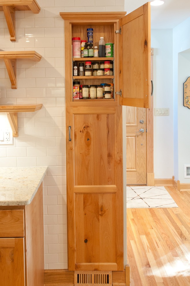 Exemple d'une cuisine ouverte chic en bois brun et U de taille moyenne avec un placard à porte shaker, un évier encastré, un plan de travail en granite, une crédence blanche, une crédence en carreau de porcelaine, un électroménager en acier inoxydable et un sol en bois brun.