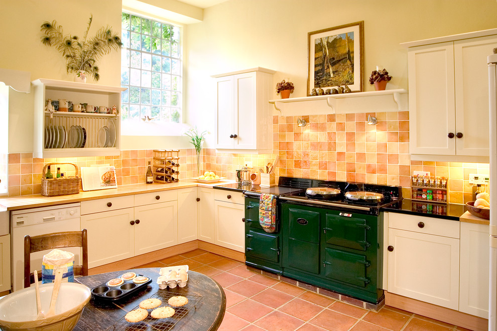 Bild på ett lantligt kök och matrum, med skåp i shakerstil, vita skåp, träbänkskiva, klinkergolv i terrakotta, en rustik diskho, orange stänkskydd och färgglada vitvaror