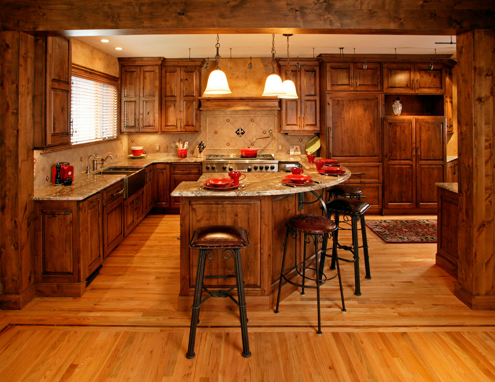 Photo of a rustic kitchen in Denver with a belfast sink, raised-panel cabinets, medium wood cabinets, beige splashback and integrated appliances.