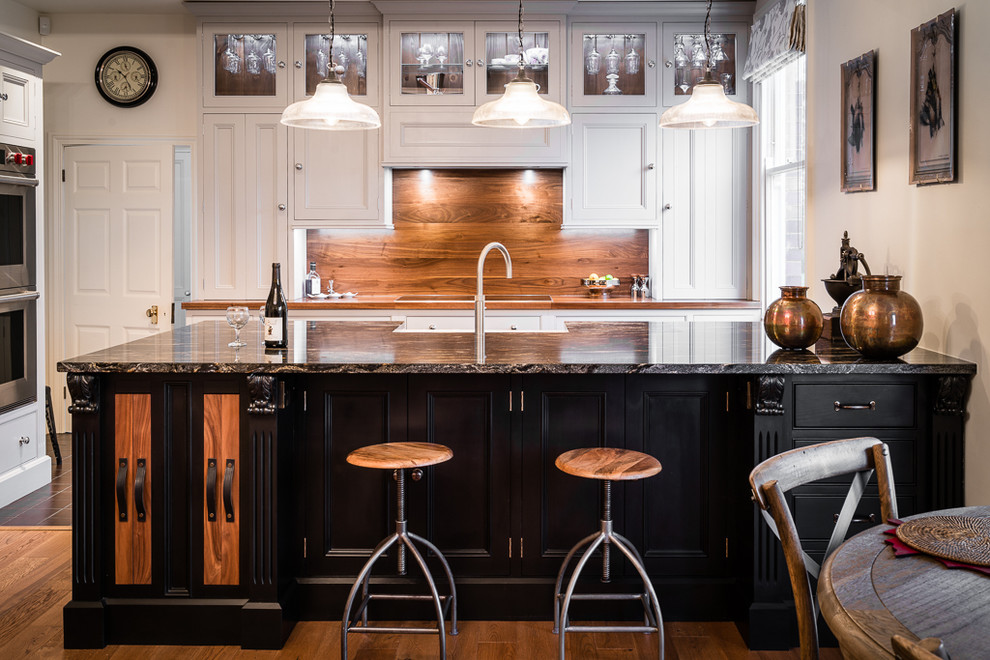 Große Klassische Küche mit Schrankfronten mit vertiefter Füllung, schwarzen Schränken, Granit-Arbeitsplatte und Kücheninsel in Sonstige