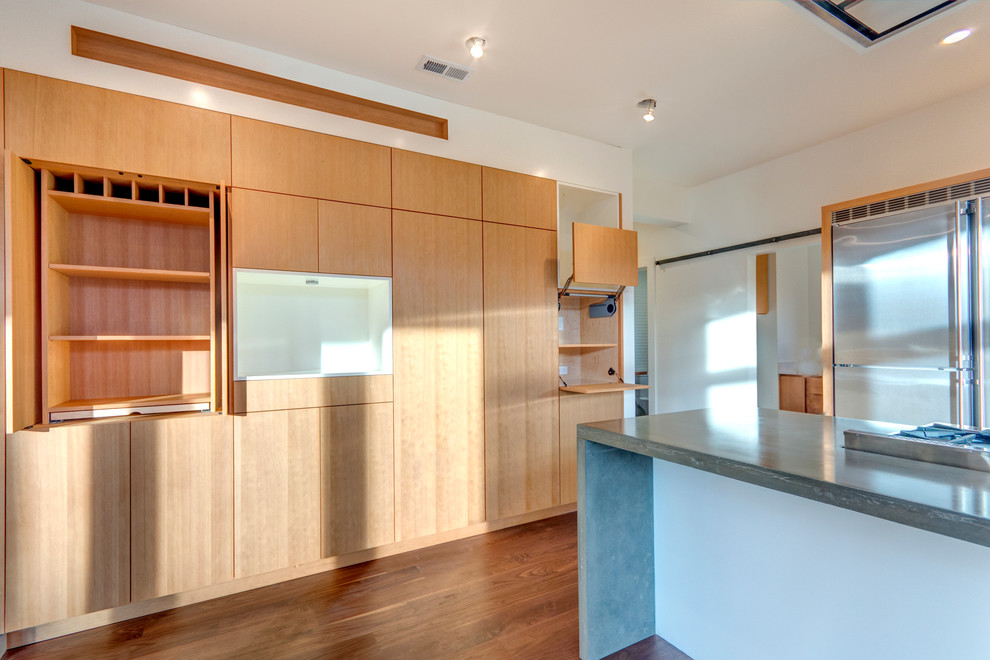 Идея дизайна: угловая кухня-гостиная среднего размера в современном стиле с врезной мойкой, плоскими фасадами, белыми фасадами, столешницей из бетона, техникой из нержавеющей стали, паркетным полом среднего тона и островом