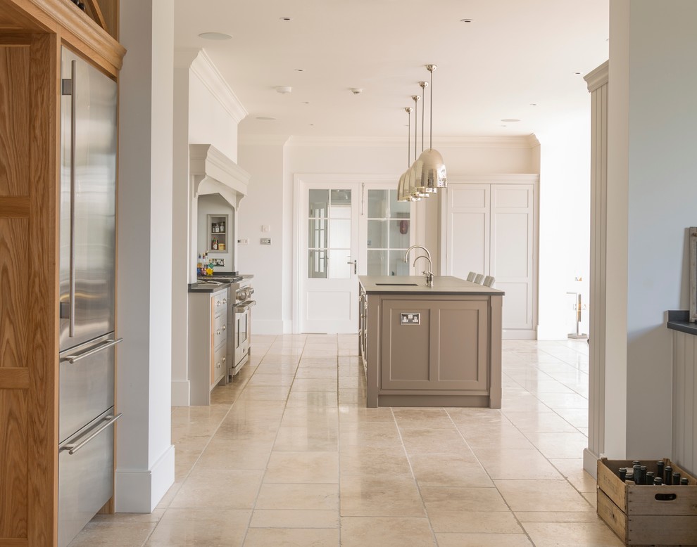 Inspiration for an expansive traditional single-wall open plan kitchen in Essex with an island, a belfast sink, flat-panel cabinets, grey cabinets, quartz worktops, stainless steel appliances and limestone flooring.