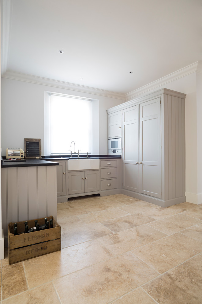 Design ideas for an expansive traditional single-wall open plan kitchen in Essex with a belfast sink, flat-panel cabinets, grey cabinets, quartz worktops, limestone flooring and an island.