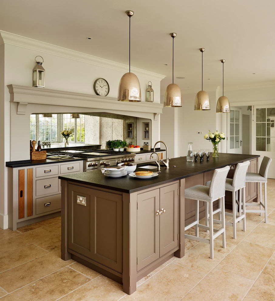 Inspiration for an expansive classic single-wall open plan kitchen in Essex with a belfast sink, flat-panel cabinets, grey cabinets, quartz worktops, metallic splashback, mirror splashback, stainless steel appliances, limestone flooring and an island.