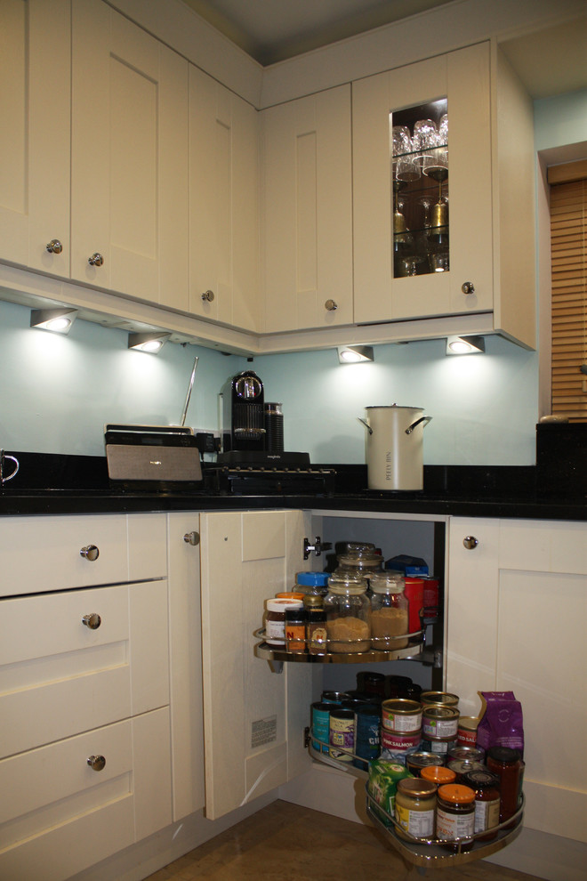 Modern inredning av ett mellanstort kök, med en undermonterad diskho, skåp i shakerstil, granitbänkskiva, rostfria vitvaror och travertin golv