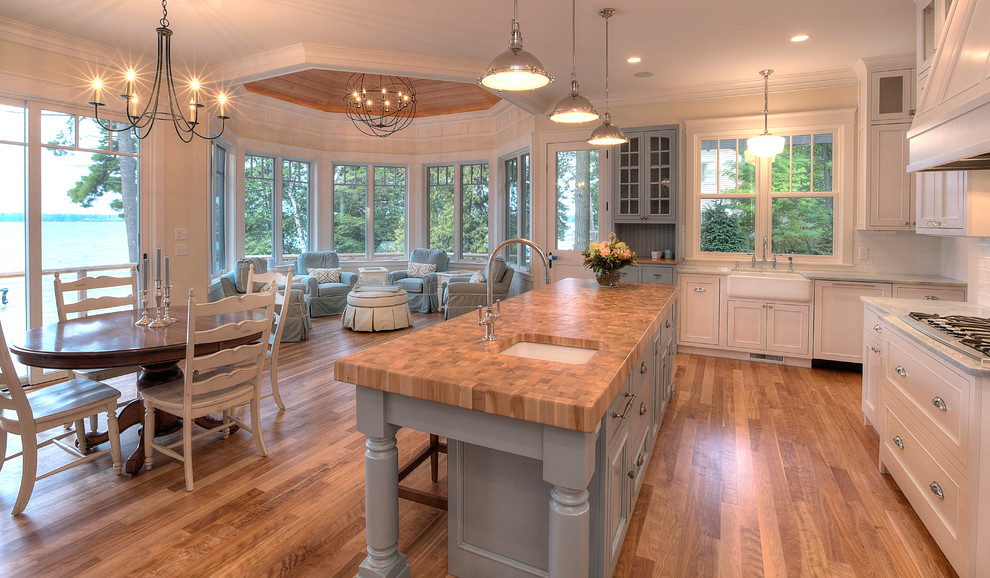 Inspiration for a coastal open concept kitchen remodel in Other with a farmhouse sink, blue cabinets and wood countertops