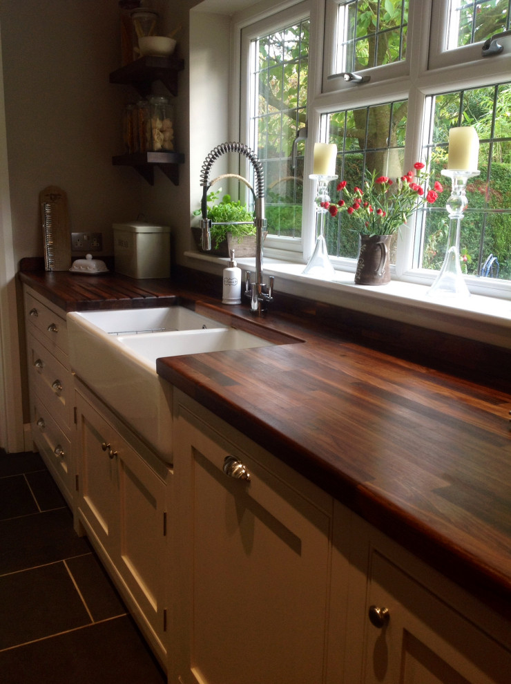 Inspiration for a medium sized traditional l-shaped open plan kitchen in Surrey with a belfast sink, beaded cabinets, beige cabinets, wood worktops, ceramic flooring, no island and grey floors.