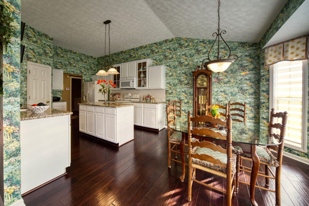 Exempel på ett mellanstort lantligt flerfärgad flerfärgat kök och matrum, med en enkel diskho, luckor med upphöjd panel, vita skåp, granitbänkskiva, vitt stänkskydd, stänkskydd i keramik, vita vitvaror, mörkt trägolv, en köksö och brunt golv