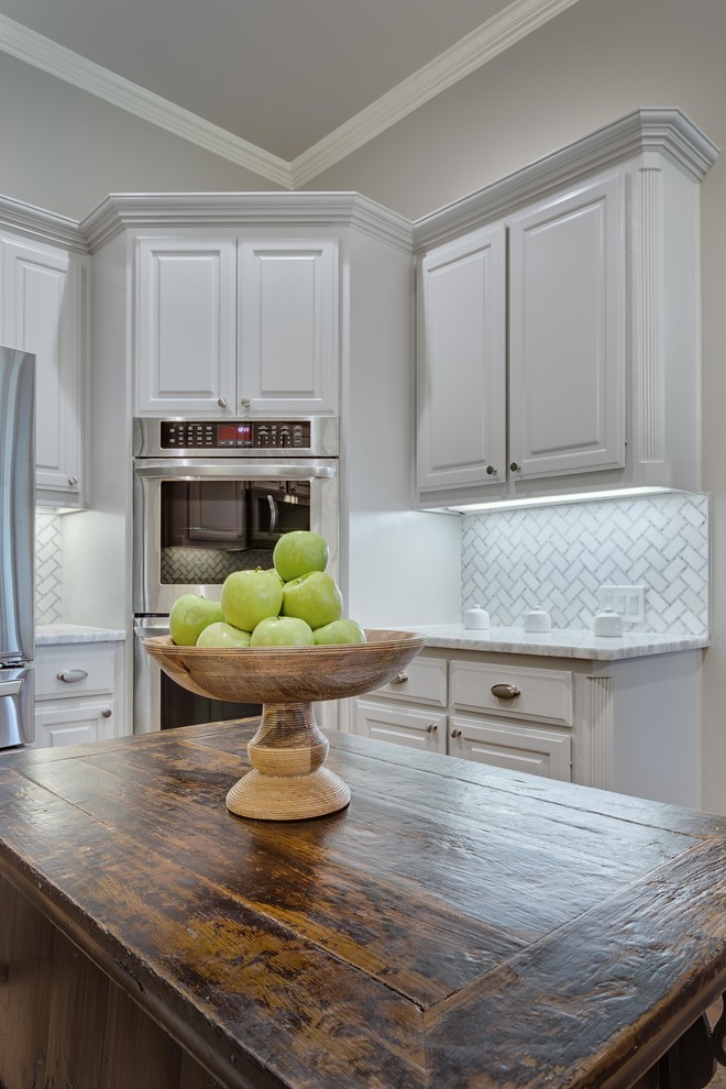 Inspiration för ett avskilt, stort vintage u-kök, med luckor med upphöjd panel, vita skåp, marmorbänkskiva, vitt stänkskydd, rostfria vitvaror, mellanmörkt trägolv och en köksö
