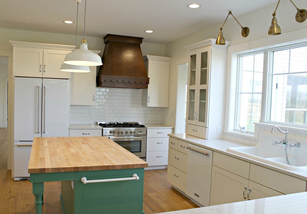 Example of a mid-sized cottage u-shaped light wood floor and beige floor eat-in kitchen design in Other with a drop-in sink, flat-panel cabinets, white cabinets, quartz countertops, white backsplash, subway tile backsplash, paneled appliances and an island