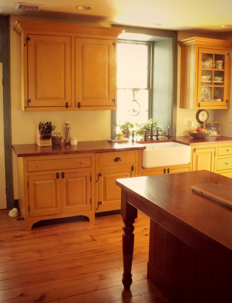 Cette photo montre une cuisine linéaire nature en bois brun de taille moyenne avec un évier de ferme, un placard avec porte à panneau surélevé, un électroménager blanc, un sol en bois brun et îlot.