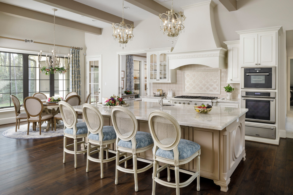 Large l-shaped kitchen/diner in Houston with white cabinets, stainless steel appliances, dark hardwood flooring, an island, brown floors, white worktops, raised-panel cabinets, beige splashback and exposed beams.