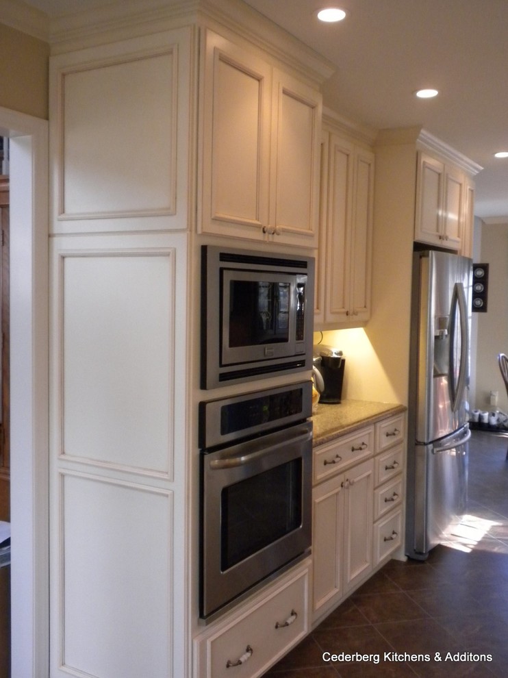 Example of a mid-sized classic galley eat-in kitchen design in Raleigh with a single-bowl sink, flat-panel cabinets, beige cabinets, granite countertops, beige backsplash, mosaic tile backsplash, stainless steel appliances and no island