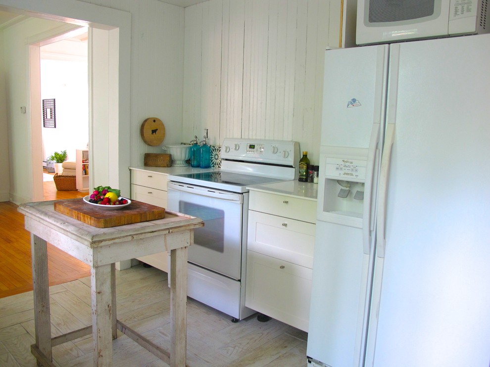 Inspiration for a small shabby-chic style single-wall light wood floor and white floor enclosed kitchen remodel in New York with shaker cabinets, white cabinets, solid surface countertops, white backsplash, wood backsplash, white appliances and an island