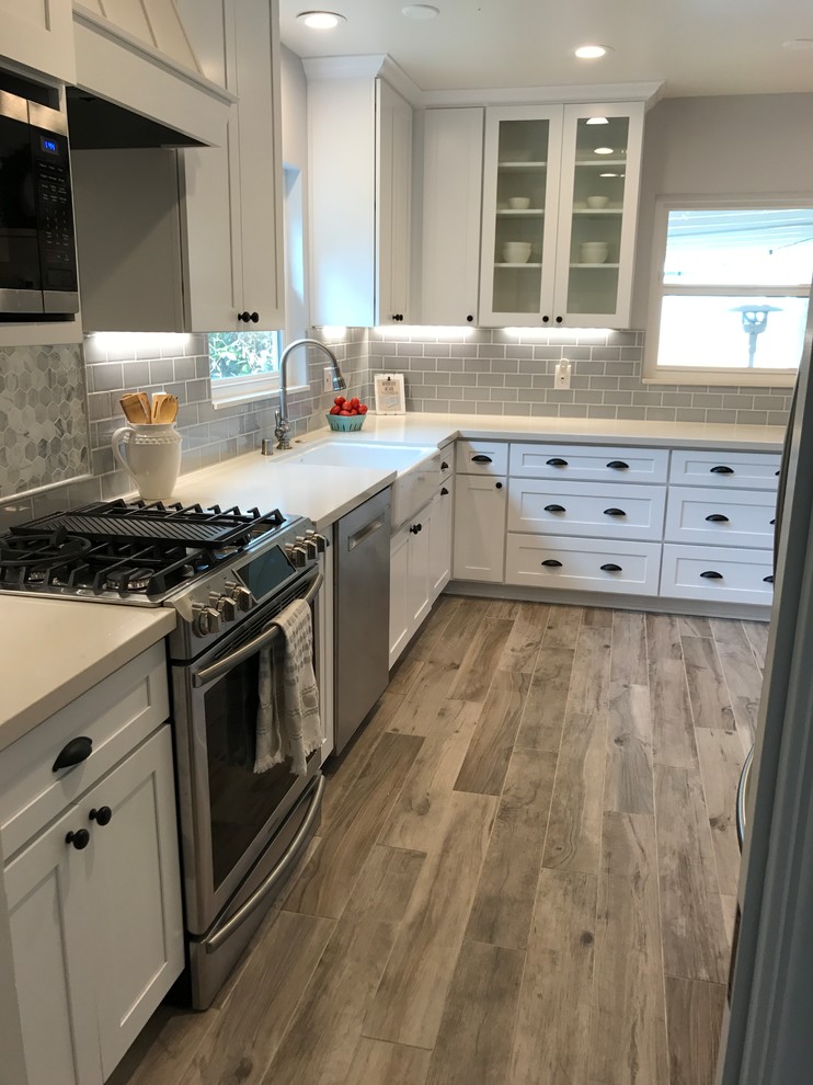 Inspiration for a mid-sized country u-shaped porcelain tile and gray floor eat-in kitchen remodel in Los Angeles with a farmhouse sink, shaker cabinets, white cabinets, quartz countertops, gray backsplash, ceramic backsplash, stainless steel appliances and a peninsula