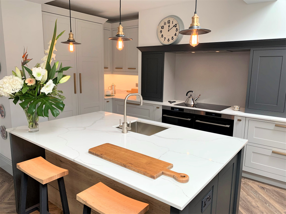 Immagine di una cucina minimal di medie dimensioni con lavello a vasca singola, ante in stile shaker, ante in legno scuro, top in quarzite, elettrodomestici neri e pavimento in vinile