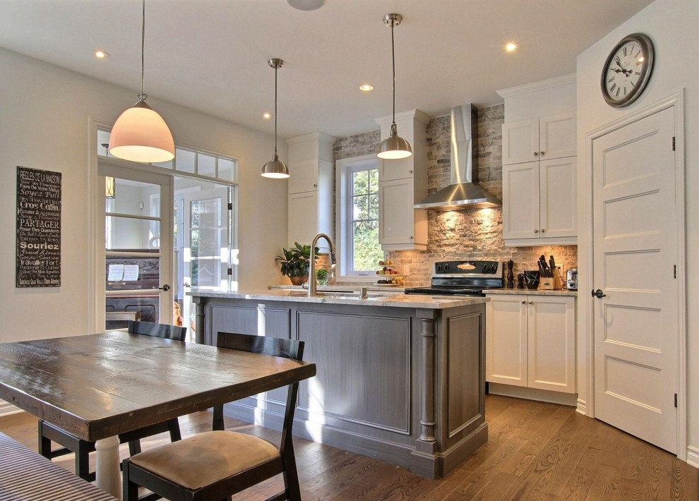 Exempel på ett mellanstort klassiskt grå grått kök, med en undermonterad diskho, vita skåp, granitbänkskiva, grått stänkskydd, stänkskydd i sten, rostfria vitvaror, mellanmörkt trägolv, en köksö och skåp i shakerstil