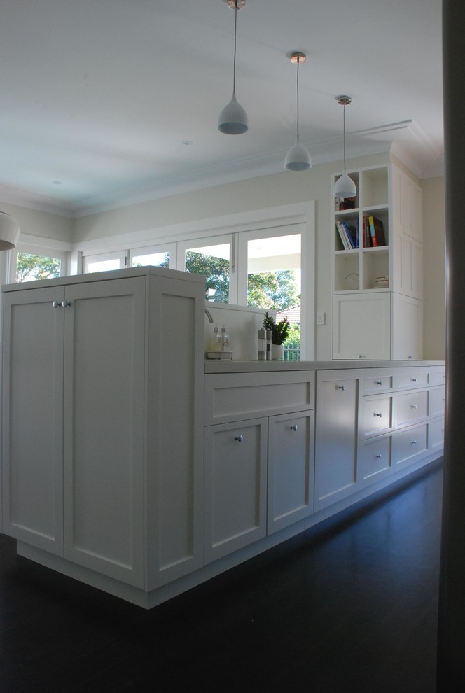 Diseño de cocina contemporánea abierta con armarios estilo shaker, puertas de armario blancas, suelo de madera oscura y península