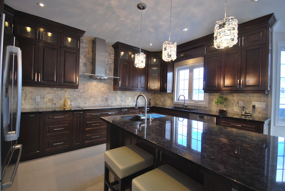 Klassisk inredning av ett stort kök, med en undermonterad diskho, luckor med upphöjd panel, bruna skåp och granitbänkskiva