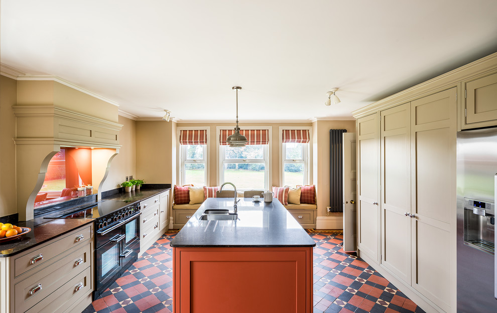 Exempel på ett mellanstort klassiskt kök, med en dubbel diskho, luckor med infälld panel, granitbänkskiva, orange stänkskydd, glaspanel som stänkskydd, svarta vitvaror, cementgolv, en köksö och flerfärgat golv