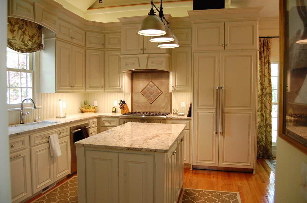 Bild på ett mellanstort vintage kök, med en undermonterad diskho, luckor med upphöjd panel, beige skåp, granitbänkskiva, vitt stänkskydd, stänkskydd i trä, integrerade vitvaror, mellanmörkt trägolv, en köksö och brunt golv
