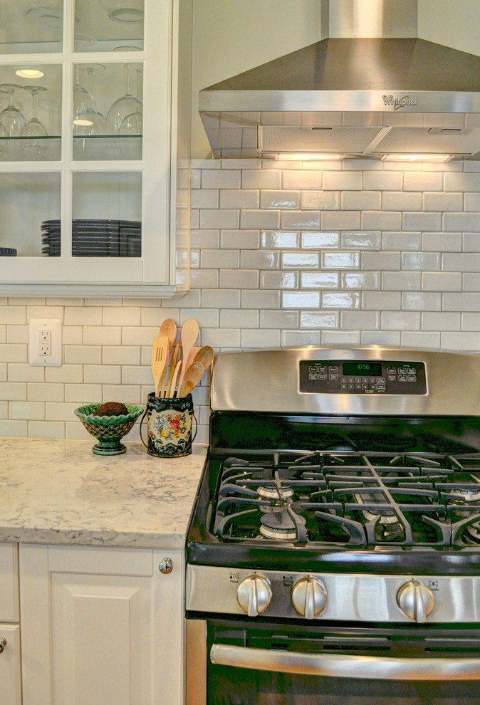 Eat-in kitchen - mid-sized traditional u-shaped light wood floor eat-in kitchen idea in DC Metro with an undermount sink, raised-panel cabinets, white cabinets, quartz countertops, white backsplash, subway tile backsplash, stainless steel appliances and a peninsula