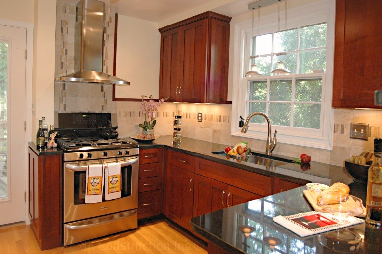 This is an example of a traditional u-shaped enclosed kitchen in DC Metro with a submerged sink, shaker cabinets, dark wood cabinets, granite worktops, multi-coloured splashback, stainless steel appliances, light hardwood flooring and a breakfast bar.