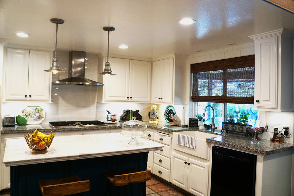 Klassisk inredning av ett mellanstort l-kök, med en rustik diskho, luckor med upphöjd panel, vita skåp, vitt stänkskydd, stänkskydd i tunnelbanekakel, svarta vitvaror, klinkergolv i terrakotta, en köksö och brunt golv