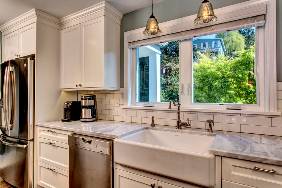 Inspiration for a timeless kitchen remodel in Seattle with a farmhouse sink, raised-panel cabinets, white cabinets, white backsplash, subway tile backsplash and stainless steel appliances