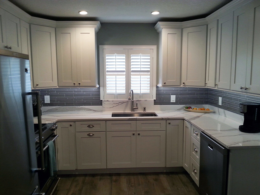 This is an example of a small classic u-shaped kitchen/diner in Orlando with a submerged sink, shaker cabinets, white cabinets, engineered stone countertops, grey splashback, glass tiled splashback, stainless steel appliances, porcelain flooring and brown floors.