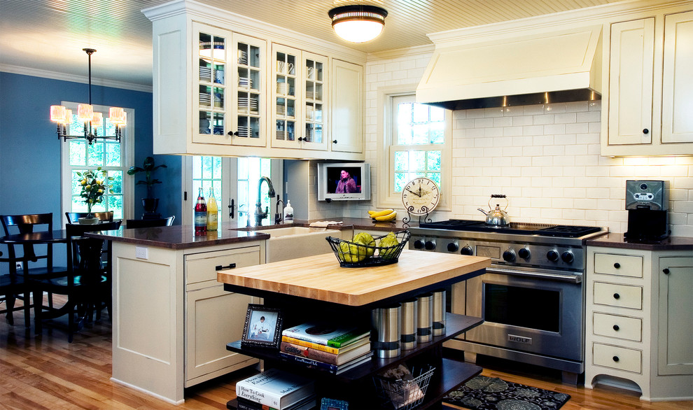 Diseño de cocina comedor clásica con armarios estilo shaker, puertas de armario beige, salpicadero beige, salpicadero de azulejos tipo metro y electrodomésticos de acero inoxidable