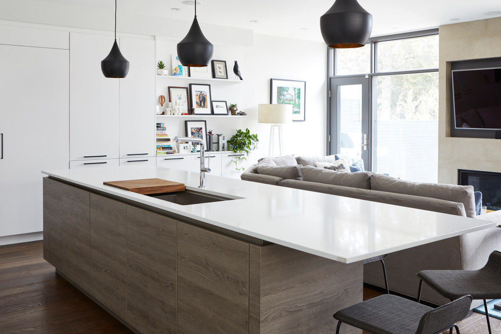 Example of a large minimalist l-shaped medium tone wood floor and brown floor kitchen design in Toronto with an undermount sink, flat-panel cabinets, gray cabinets, quartz countertops, white backsplash, stone slab backsplash, paneled appliances, an island and white countertops