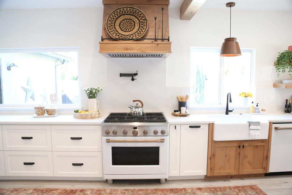 Idéer för att renovera ett stort funkis vit linjärt vitt kök och matrum, med en rustik diskho, skåp i shakerstil, vita skåp, bänkskiva i kvarts, vitt stänkskydd, vita vitvaror, laminatgolv, en köksö och grått golv