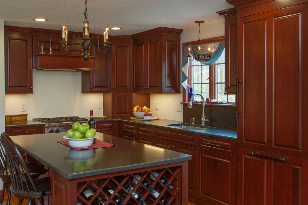 This is an example of a traditional l-shaped kitchen/diner in Boston with a built-in sink, raised-panel cabinets, dark wood cabinets, composite countertops, medium hardwood flooring and an island.