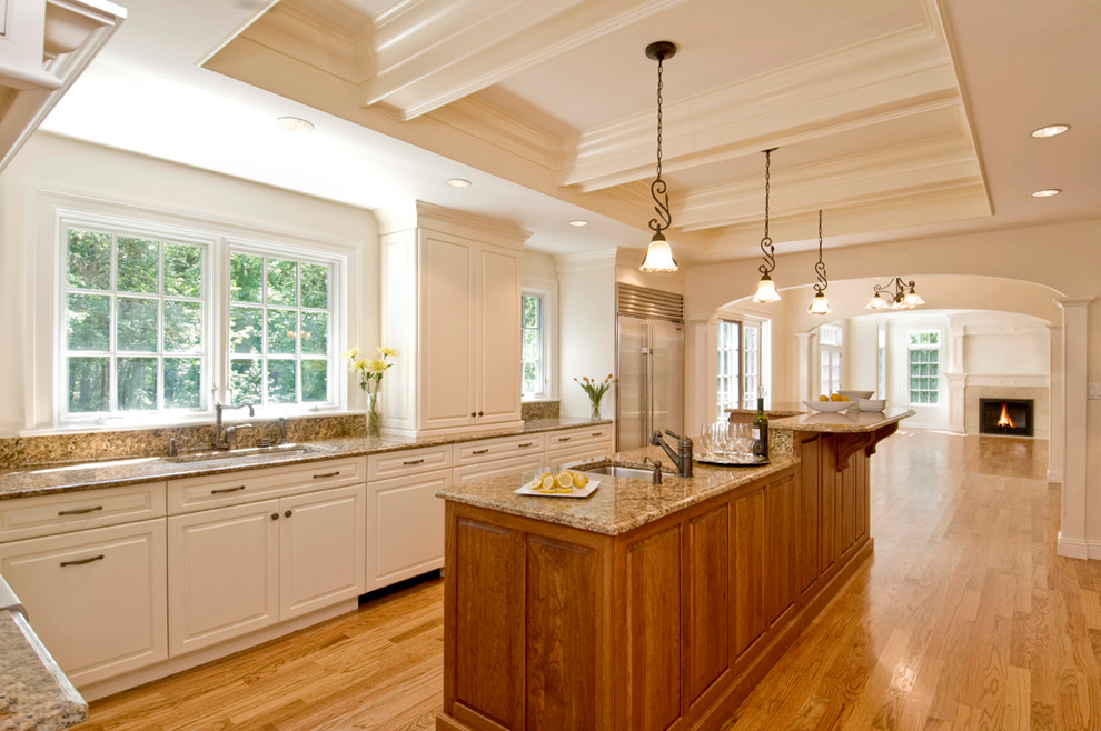 This is an example of a traditional l-shaped enclosed kitchen in Boston with a submerged sink, raised-panel cabinets, white cabinets, granite worktops and stainless steel appliances.