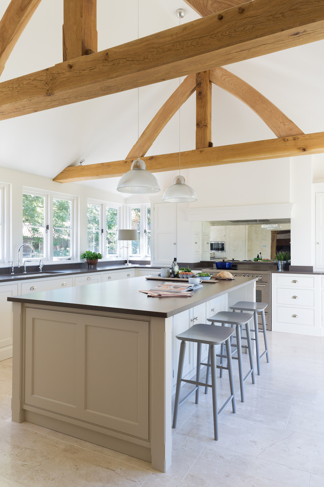 Inspiration for a large rural l-shaped open plan kitchen in Essex with a submerged sink, white cabinets, stainless steel appliances, limestone flooring, an island, recessed-panel cabinets and mirror splashback.