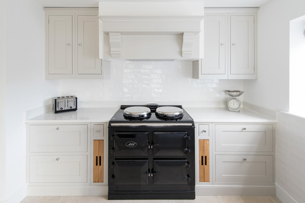 This is an example of a medium sized classic galley open plan kitchen in Devon with a built-in sink, shaker cabinets, grey cabinets, composite countertops, grey splashback, ceramic splashback, stainless steel appliances, limestone flooring and a breakfast bar.