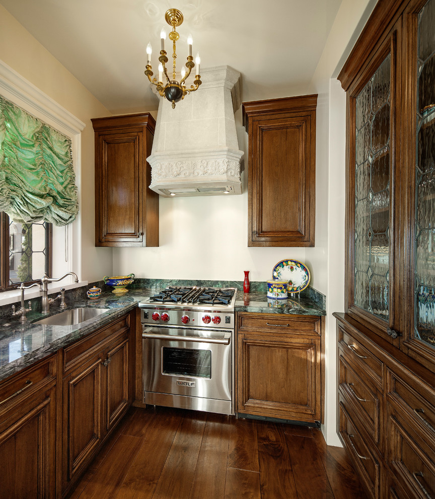Example of a tuscan eat-in kitchen design in Santa Barbara with a farmhouse sink, dark wood cabinets, marble countertops, multicolored backsplash, ceramic backsplash and paneled appliances