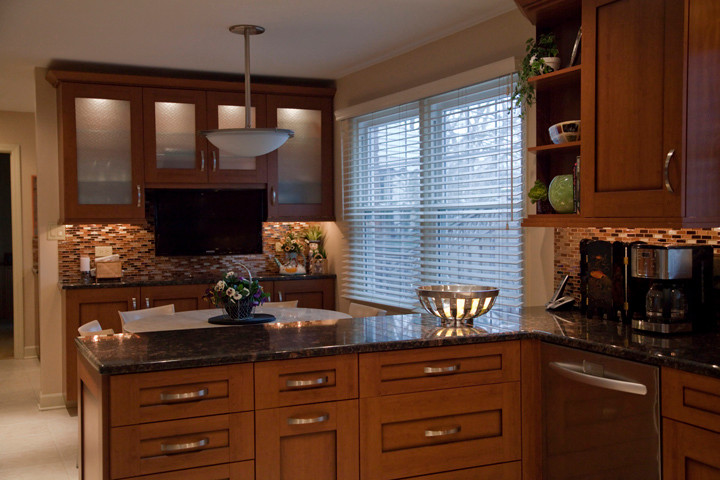 Inredning av ett klassiskt mellanstort kök, med en undermonterad diskho, luckor med infälld panel, skåp i mellenmörkt trä, brunt stänkskydd, rostfria vitvaror och klinkergolv i porslin